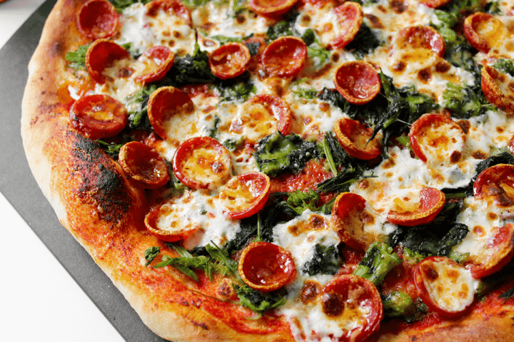 close up on pepperoni pizza with broccoli rabe and hot honey