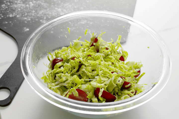 shredded Brussels sprouts and halved grapes in bowl