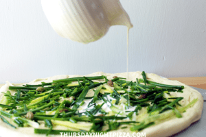 pouring cream on simple white pizza before baking