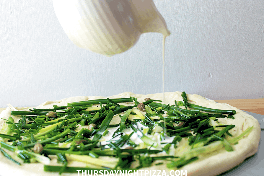 pouring cream on simple white pizza before baking