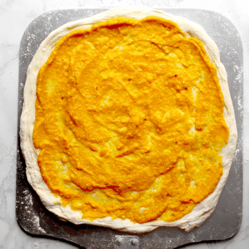 Pumpkin Pizza and Pasta Sauce spread on a round of pizza dough