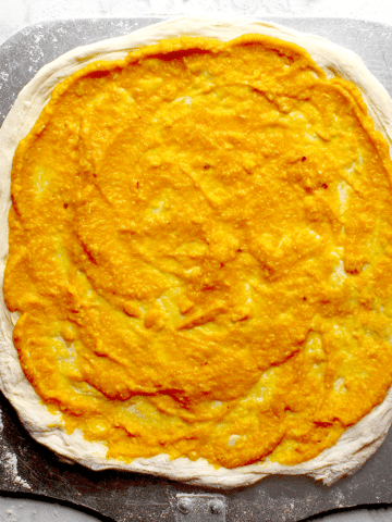 Pumpkin Pizza and Pasta Sauce spread on a round of pizza dough