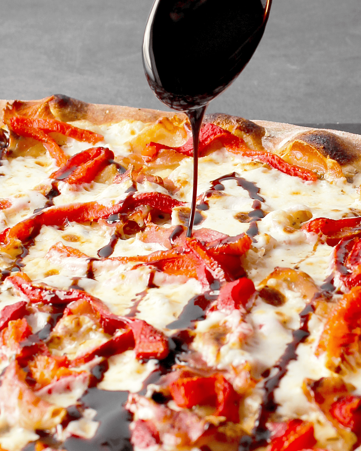 drizzling homemade balsamic glaze on pizza