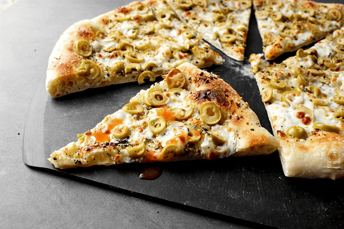 olive everything pizza topped with hot sauce