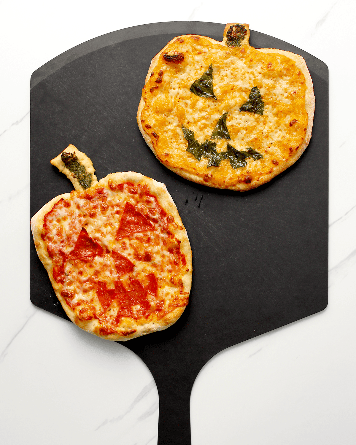 jack-o-lantern pizzas on pizza peel