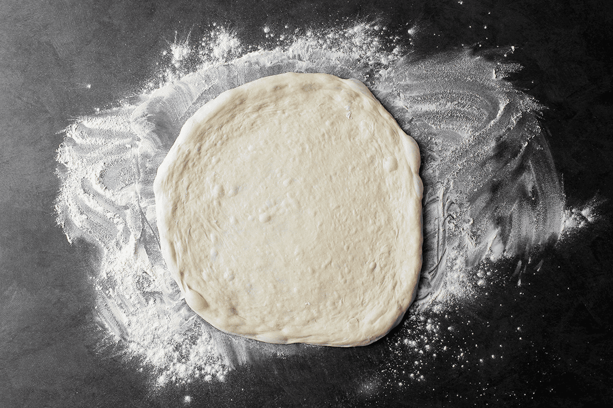 stretched-out pizza dough on counter